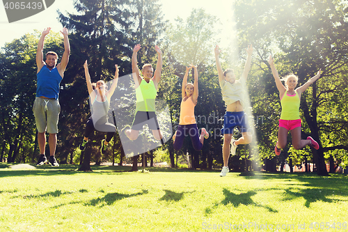 Image of group of happy friends jumping high outdoors