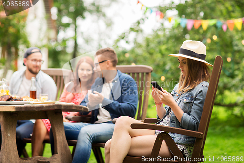 Image of woman with smartphone and friends at summer party