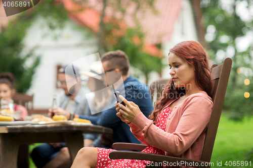 Image of woman with smartphone and friends at summer party