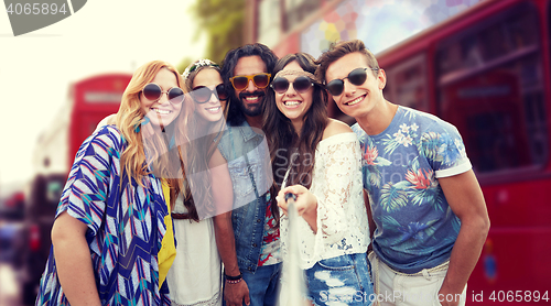 Image of smiling hippie friends with selfie stick in london