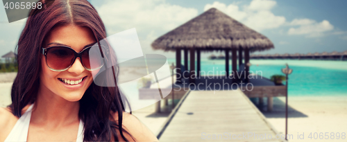 Image of smiling young woman with sunglasses on beach