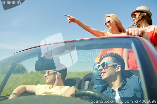 Image of happy friends driving in cabriolet car at country