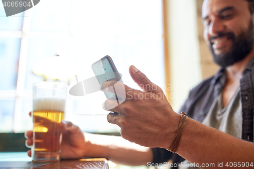 Image of close up of man with smartphone and beer at pub