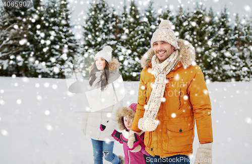 Image of happy family in winter clothes walking outdoors
