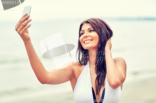 Image of smiling young woman taking selfie with smartphone