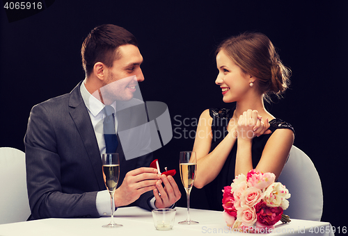 Image of man proposing to his girlfriend at restaurant