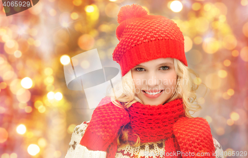 Image of happy woman in hat, scarf and mittens over lights