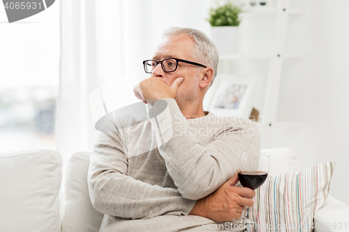 Image of senior man drinking red wine from glass at home