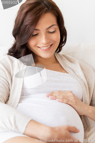 Image of happy pregnant woman lying on bed at home