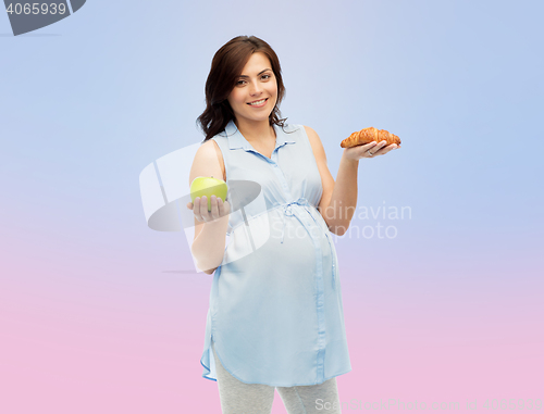 Image of happy pregnant woman with apple and croissant