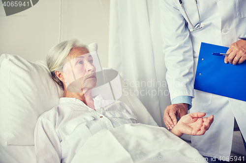 Image of doctor checking senior woman pulse at hospital