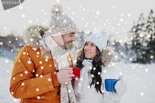 Image of happy couple with tea cups over winter landscape