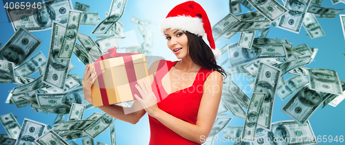 Image of beautiful woman in santa hat with gift over money