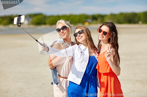 Image of group of smiling women taking selfie on beach