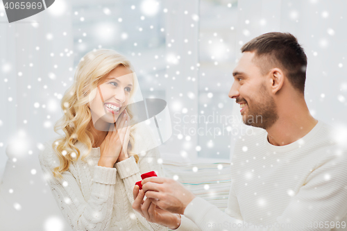 Image of happy man giving engagement ring to woman at home