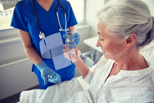 Image of nurse giving medicine to senior woman at hospital