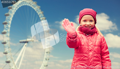 Image of happy little girl waving hand over ferry wheel