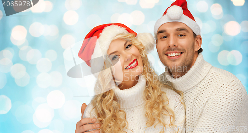 Image of happy family couple in sweaters and santa hats