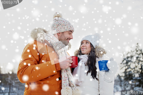 Image of happy couple with tea cups over winter landscape