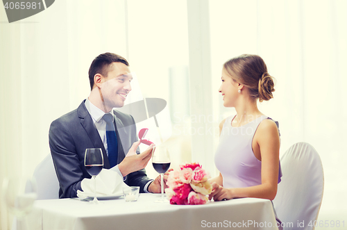 Image of man proposing to his girlfriend at restaurant