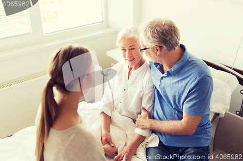 Image of happy family visiting senior woman at hospital