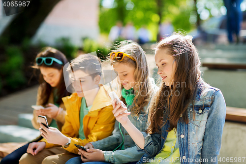 Image of happy teenage friends with smartphones outdoors