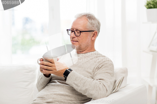 Image of happy senior man with cup of tea at home