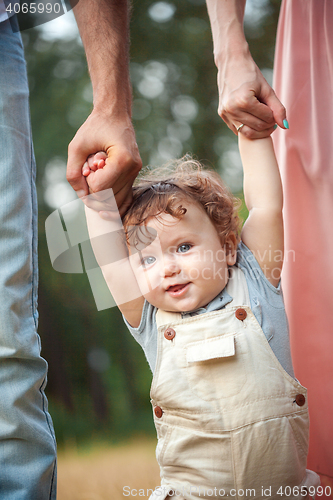 Image of Young beautiful father, mother and little toddler son against green trees