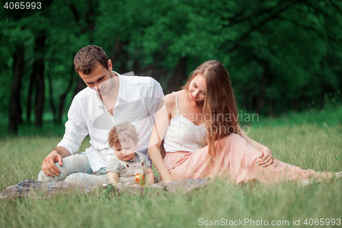 Image of Young beautiful father, mother and little toddler son against green trees