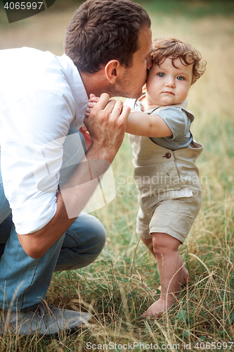 Image of Young beautiful father and little toddler son against green grass