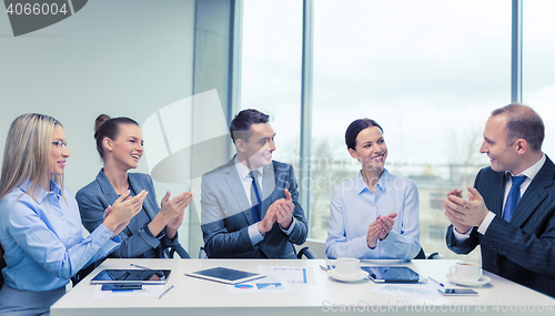 Image of business team with laptop clapping hands