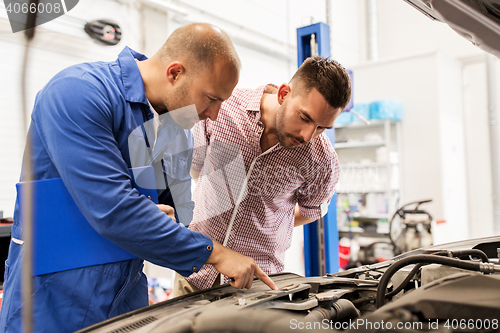 Image of auto mechanic with clipboard and man at car shop