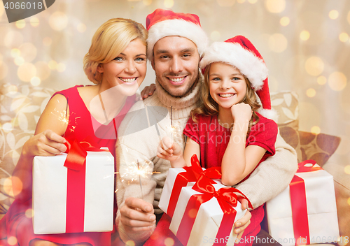 Image of smiling family holding gift boxes and sparkles