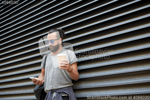 Image of man with coffee texting on smartphone in city