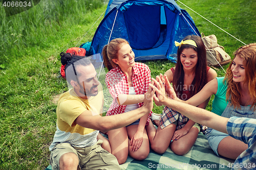 Image of happy friends making high five at camping