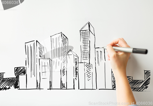 Image of close up of hand drawing city on white board