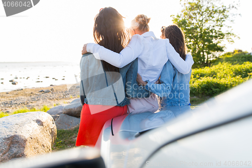 Image of happy teenage girls or women near car at seaside