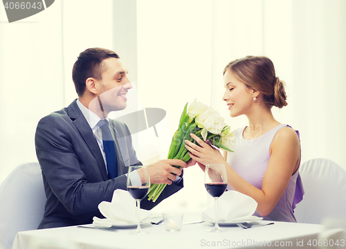 Image of smiling man giving flower bouquet at restaurant