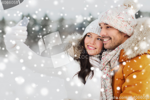 Image of happy couple taking selfie by smartphone in winter