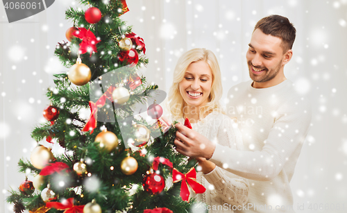 Image of happy couple decorating christmas tree at home