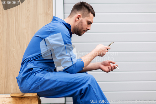 Image of auto mechanic smoking cigarette at car workshop