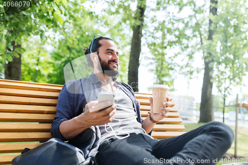 Image of man with earphones and smartphone drinking coffee