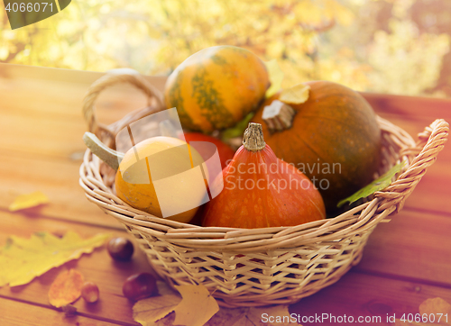 Image of close up of pumpkins in basket on wooden table