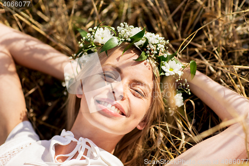 Image of happy woman in wreath of flowers lying on straw