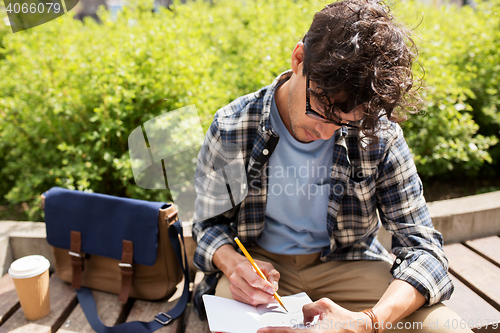 Image of man with notebook or diary writing on city street