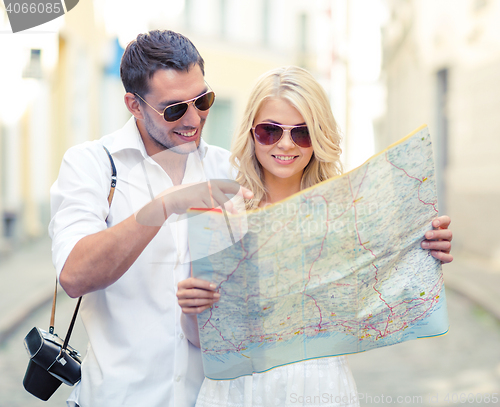 Image of smiling couple in sunglasses with map in the city