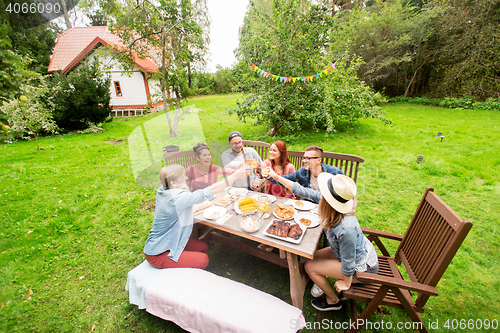 Image of happy friends having dinner at summer garden party