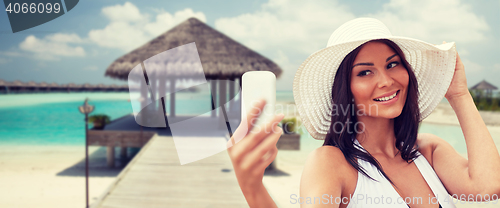 Image of young woman taking selfie with smartphone