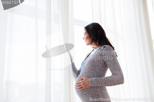Image of close up of happy pregnant woman looking to window