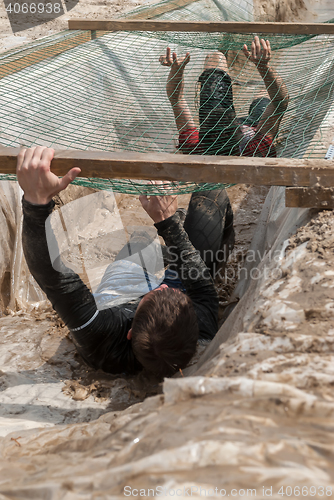 Image of Men creep on an entrenchment with sand and water